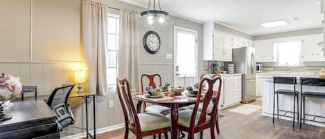 Un coin repas avec une table et des chaises en bois, un globe terrestre et une lampe sur un bureau.