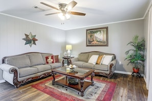 A living room with two sofas, a coffee table, a ceiling fan, a star decoration, a painting, a lamp, and a potted plant. - Cast & Relax! Ventress River Home w/ Shared Pier (Ventress)