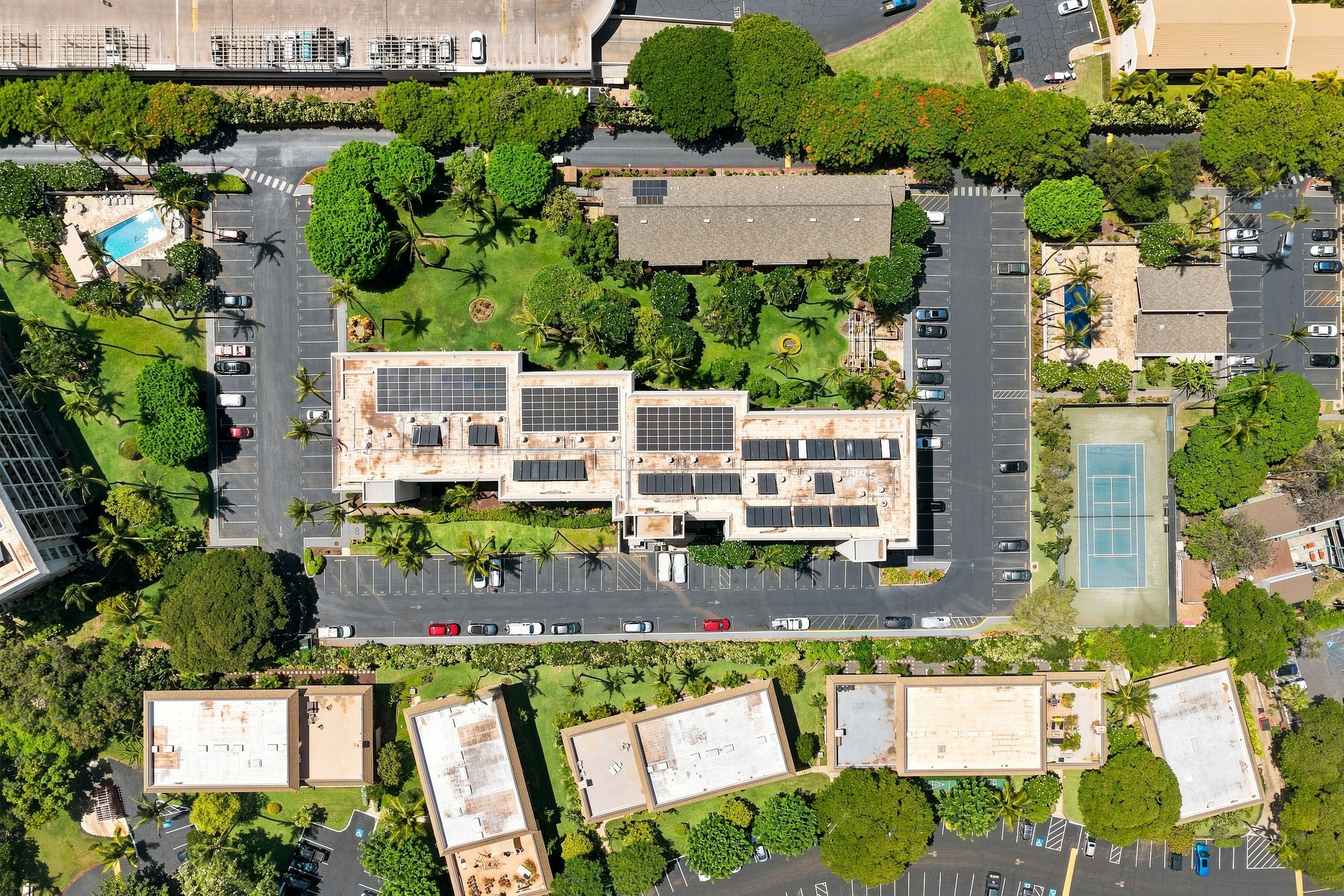 An aerial view of a hotel with multiple buildings, parking areas, and surrounding greenery.