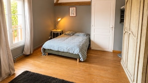 Ein Schlafzimmer mit Bett, Kleiderschrank, Nachttisch und Fenster.