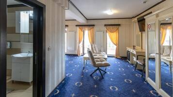 Ein Hotelzimmer mit einem großen Spiegel, einem Schreibtisch, einem Stuhl und einem blauen Teppich mit einem kreisförmigen Muster.