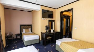 A hotel room with two beds, a desk with a chair, a mirror, and a television.