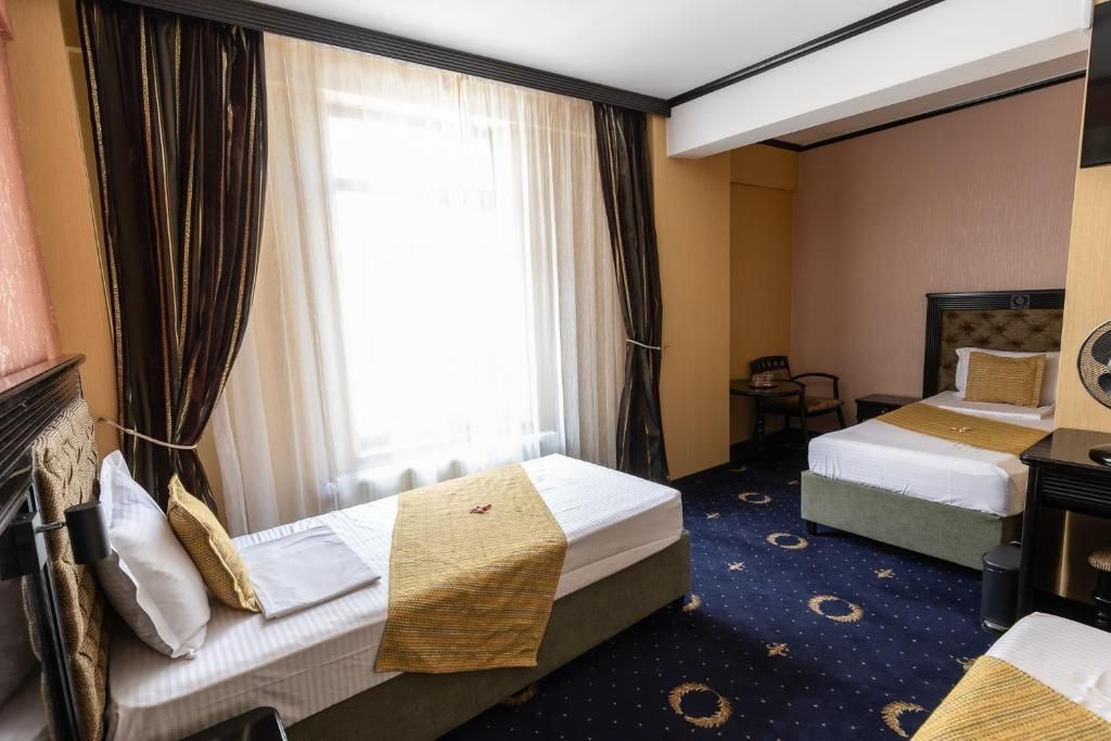 A hotel room with two beds, a desk, and a chair.