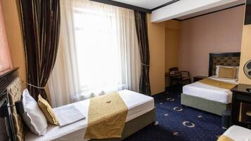 A hotel room with two beds, a desk, and a chair.