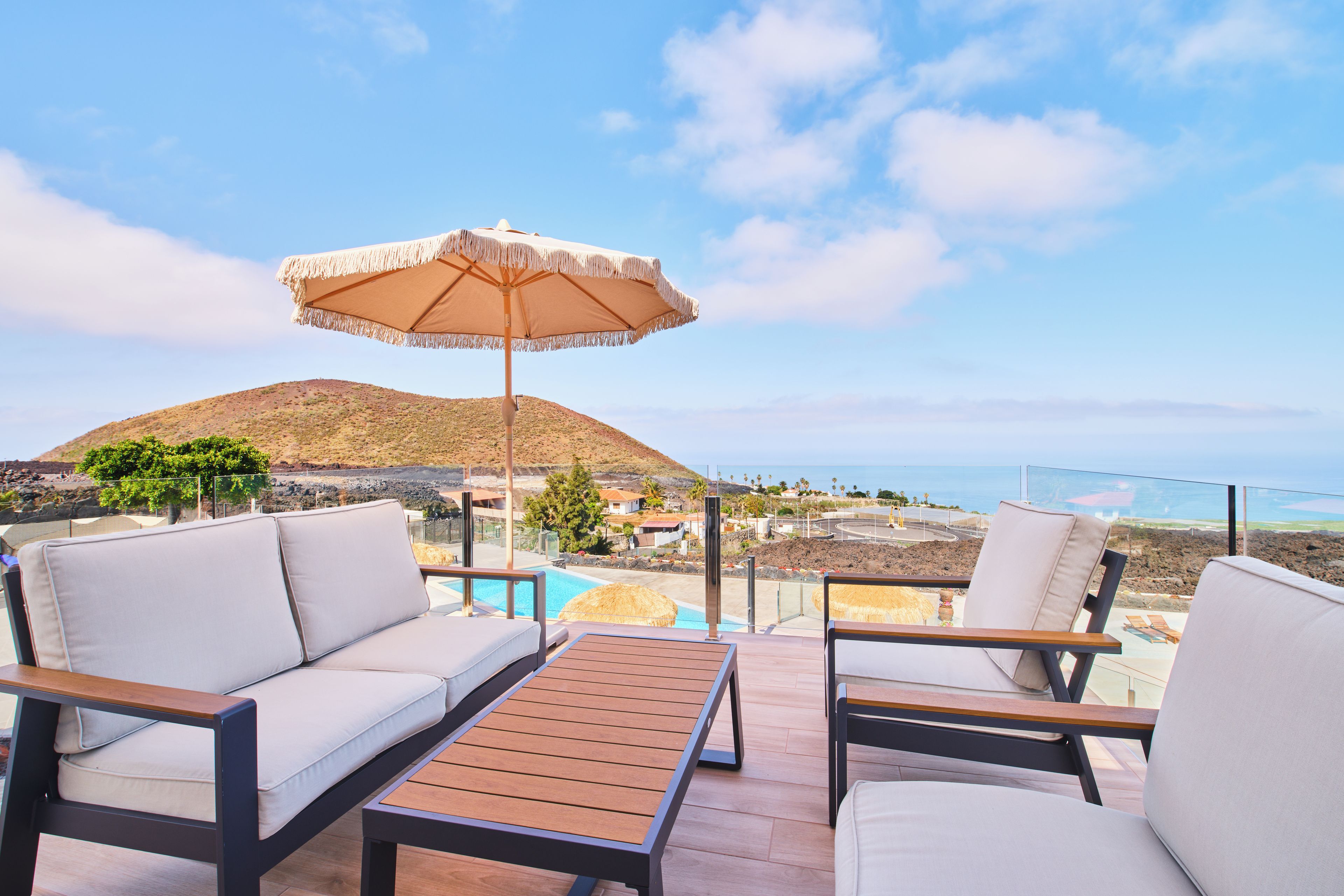 Una terraza con piscina, mobiliario exterior y vistas a la costa.