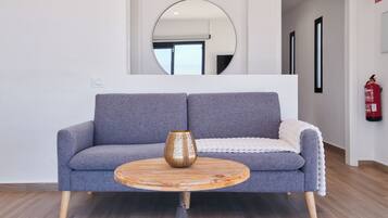 A modern living room with a grey sofa, a wooden coffee table, and a large mirror on the wall.