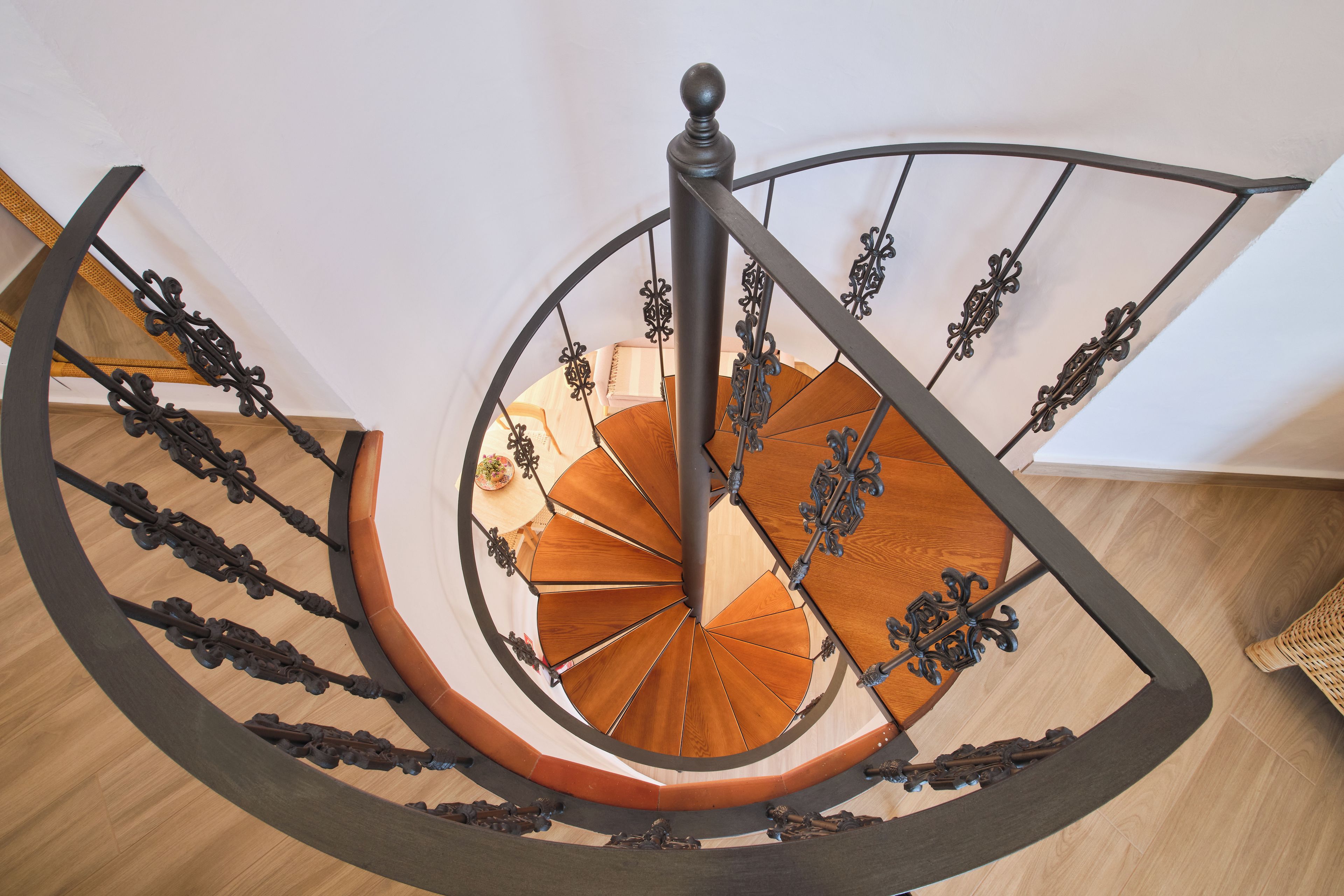Un escalier en colimaçon avec des rampes en métal ouvragé et des marches en bois.