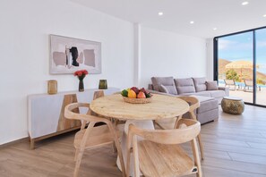 A modern living room with a dining area, a large window with a view, and a painting on the wall. - Finca el Moral  (Los Llanos)