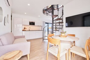 A modern kitchen with white cabinets, a built-in oven, and a dining area with a round table and wicker chairs. - Finca el Moral  (Los Llanos)