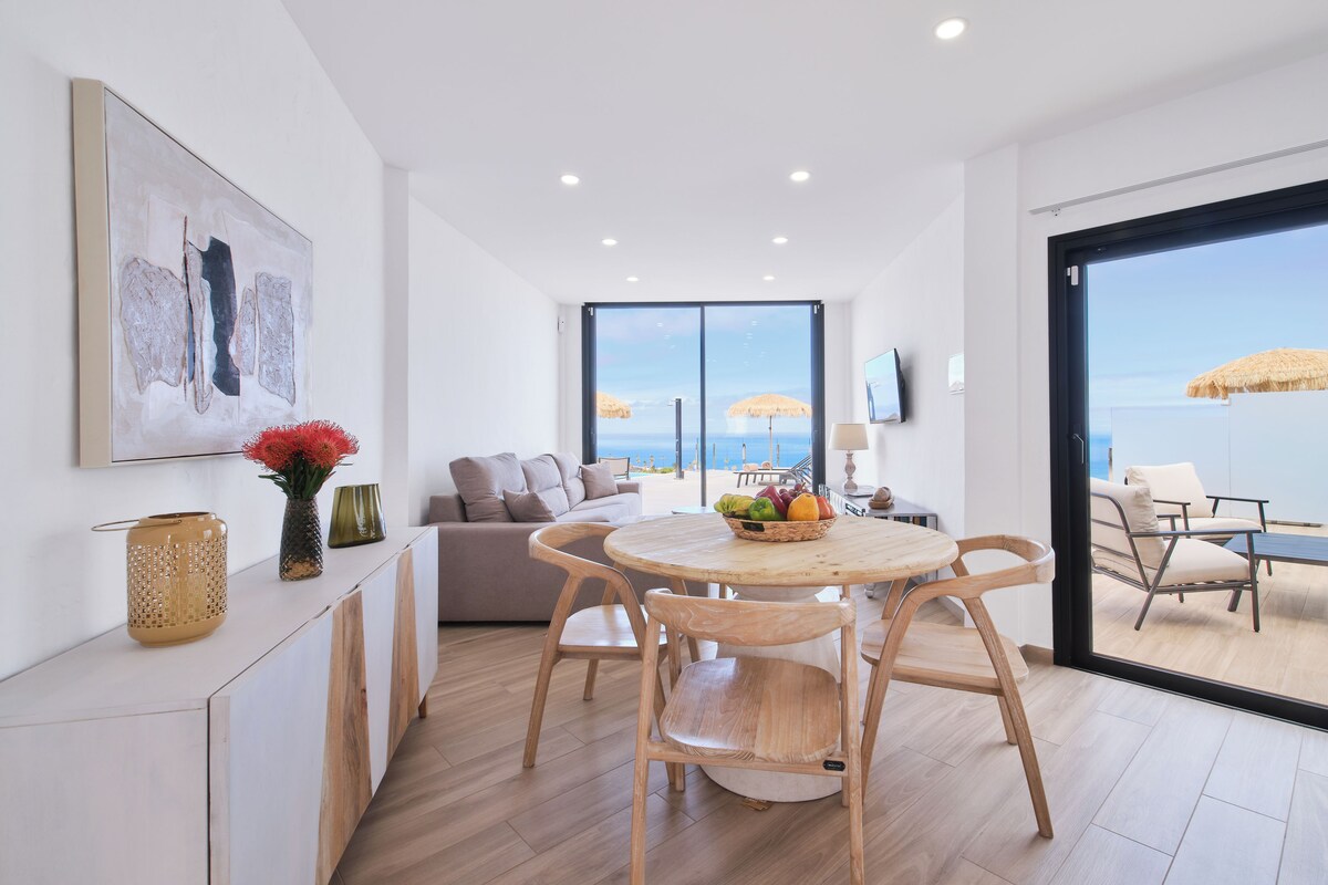 En modern inredning med ett matområde, en soffa och utsikt över havet.