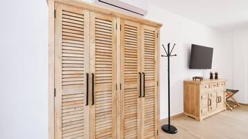 A room with a wooden wardrobe, a flat-screen TV, and a coat rack.