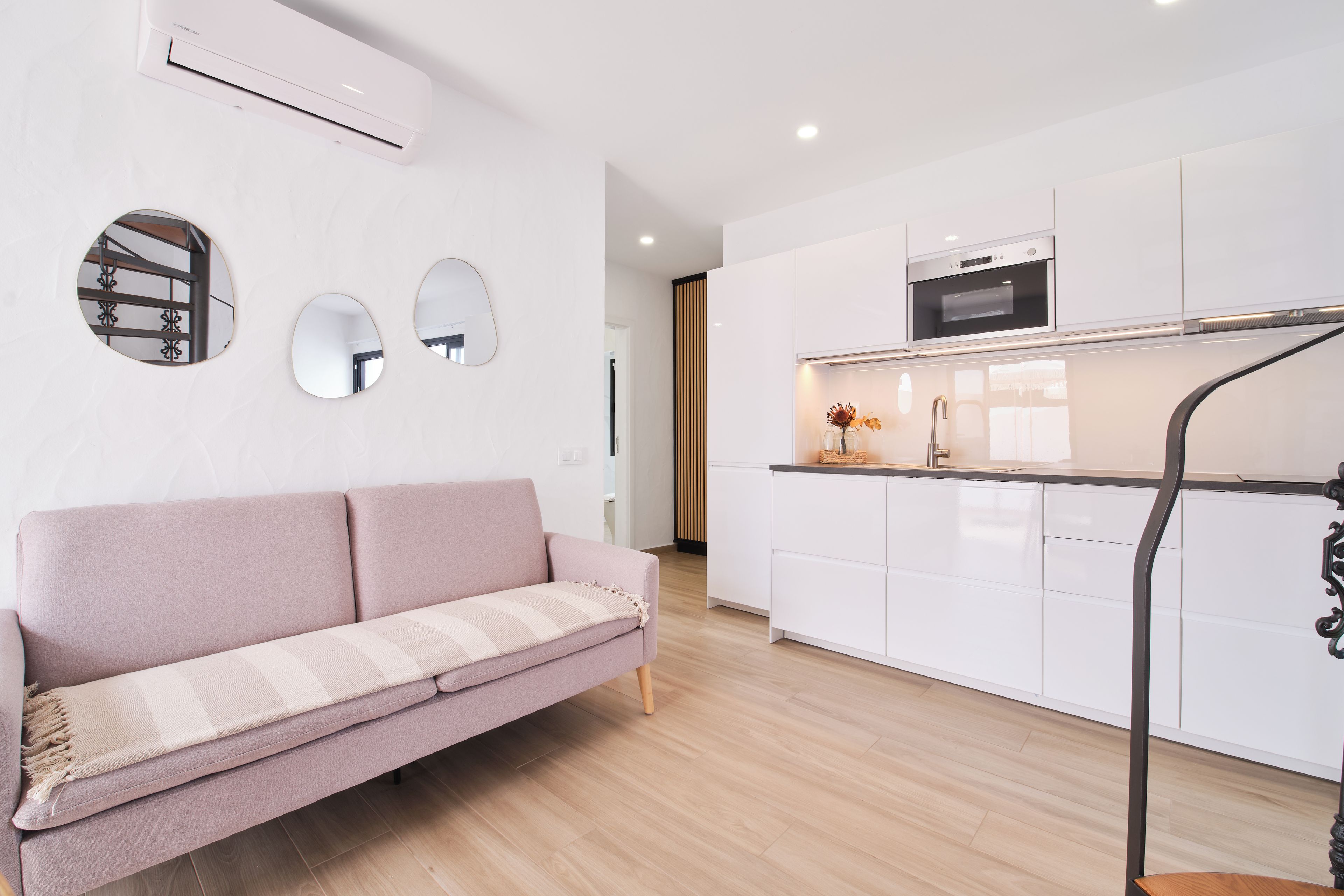 Una cocina moderna con gabinetes blancos, horno empotrado y campana extractora de acero inoxidable.