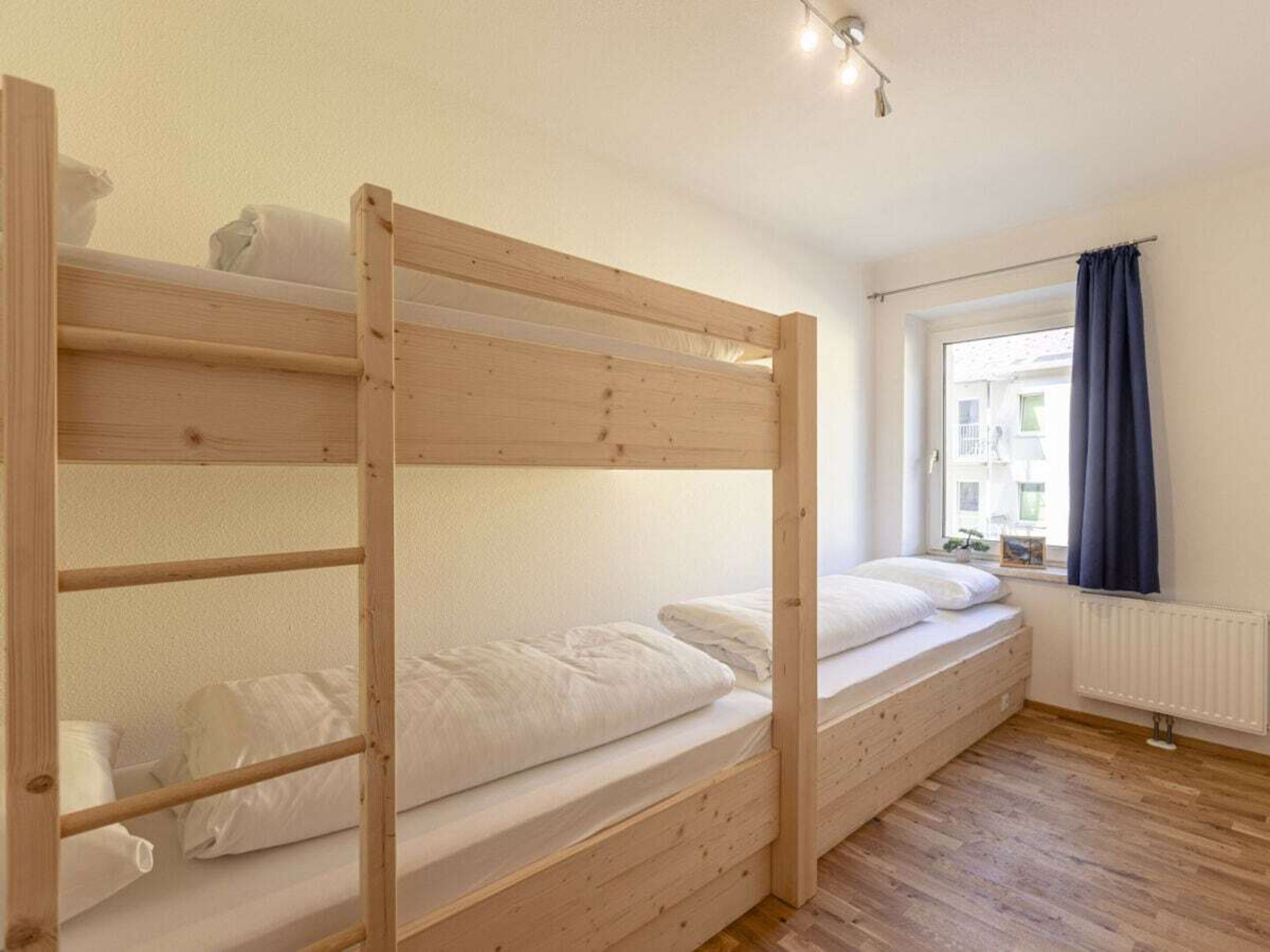 A bunk bed room with a window and a radiator.