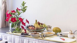 A table with a variety of fruits, a bowl of nuts, and a potted plant with red flowers. - Apartment in Eisenerz With Sauna and Balcony (Eisenerz)