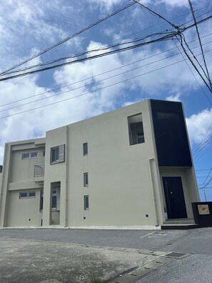 A modern two-story building with a flat facade, multiple windows, and a visible entrance. - 30-second walk to the beach. Stay like you're living here. Stunning sunset and ocean views. Beachside Island Home, Steps from the Sea (Miyakojima)