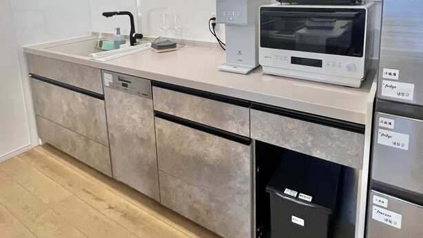 Una cocina moderna con microondas integrado, lavavajillas y un cubo de basura.
