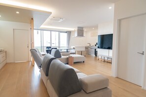 A modern living room with a sofa, a dining area, and a kitchen. - 30-second walk to the beach. Stay like you're living here. Stunning sunset and ocean views. Beachside Island Home, Steps from the Sea (Miyakojima)