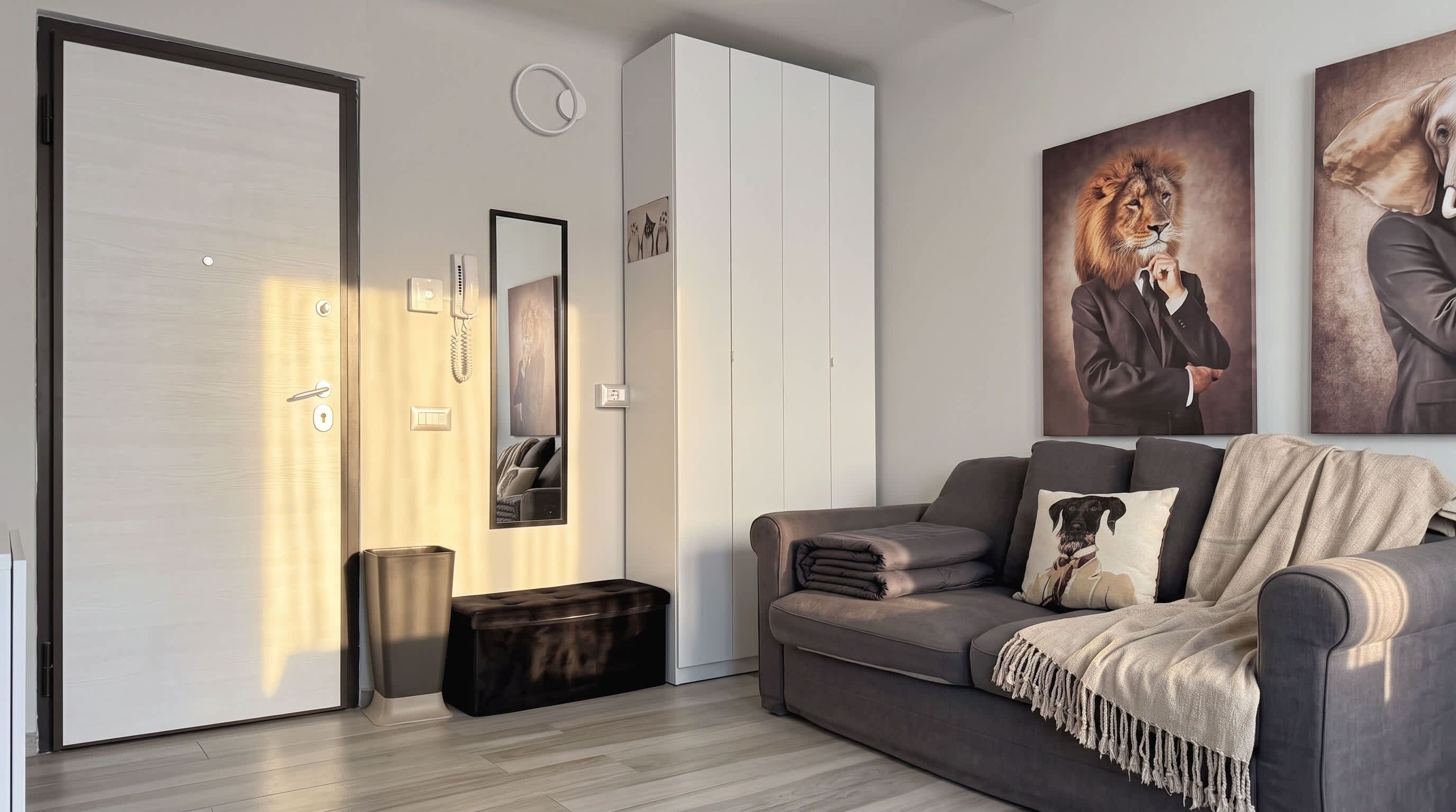 En moderne stue med en grå sofa, et stort spejl og kunst på væggene.
