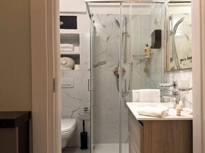 A modern bathroom with a glass-enclosed shower, a toilet, and a vanity with a mirror. - The 6th - Studio Apartment Porta Venezia (Milano)