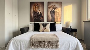 A bedroom with a large bed, two pillows, a throw blanket, and two wall art pieces. - The 6th - Studio Apartment Porta Venezia (Milano)