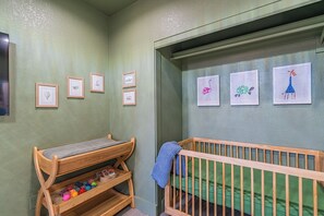 Habitación infantil con una cuna, un banco de madera y decoración en la pared.