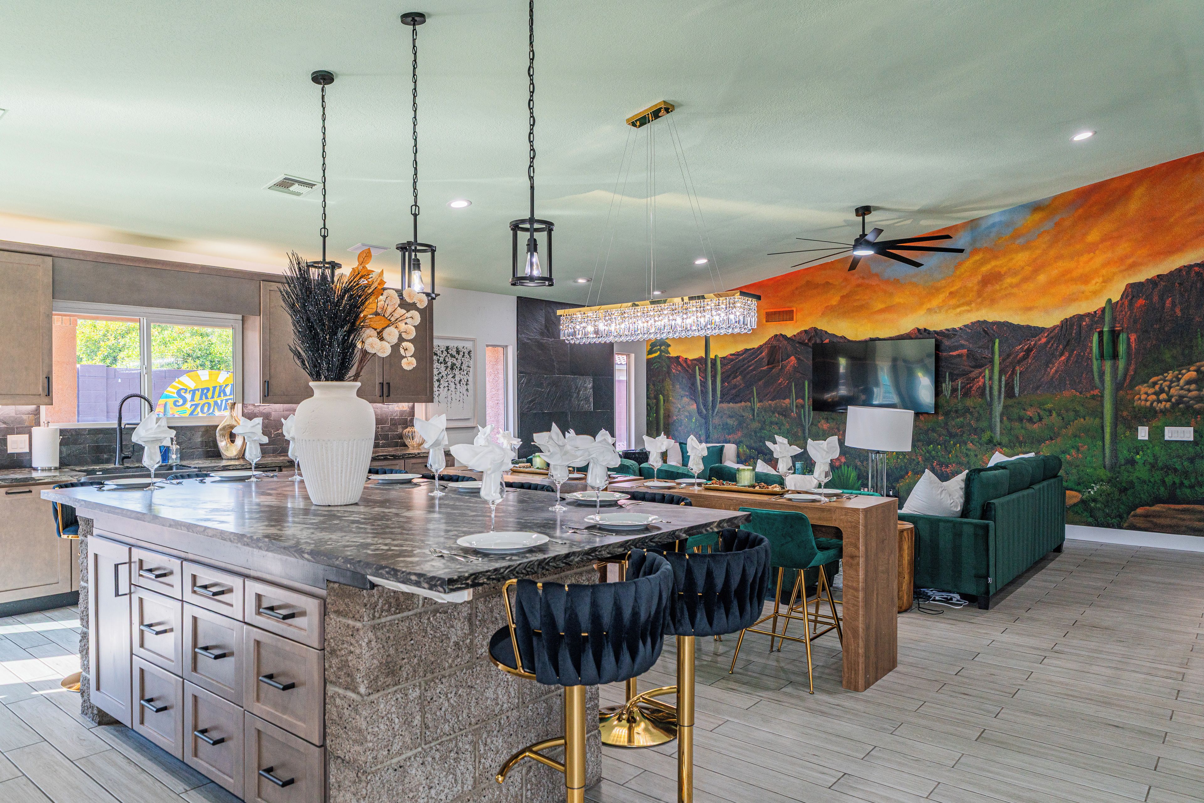A modern kitchen with a large island, bar stools, and a dining area with green upholstered furniture.