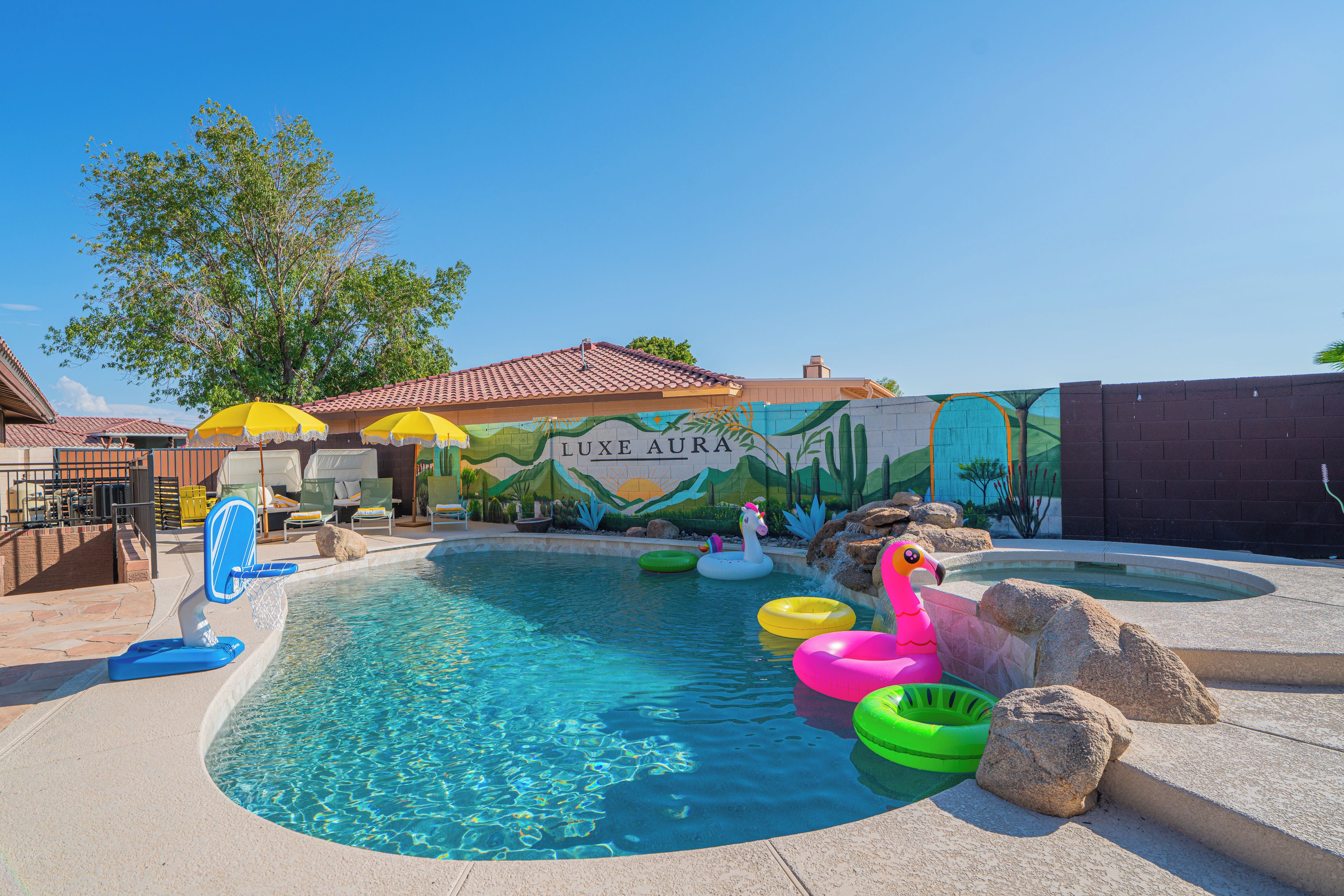 A swimming pool with inflatable toys, a mural, and lounge chairs.