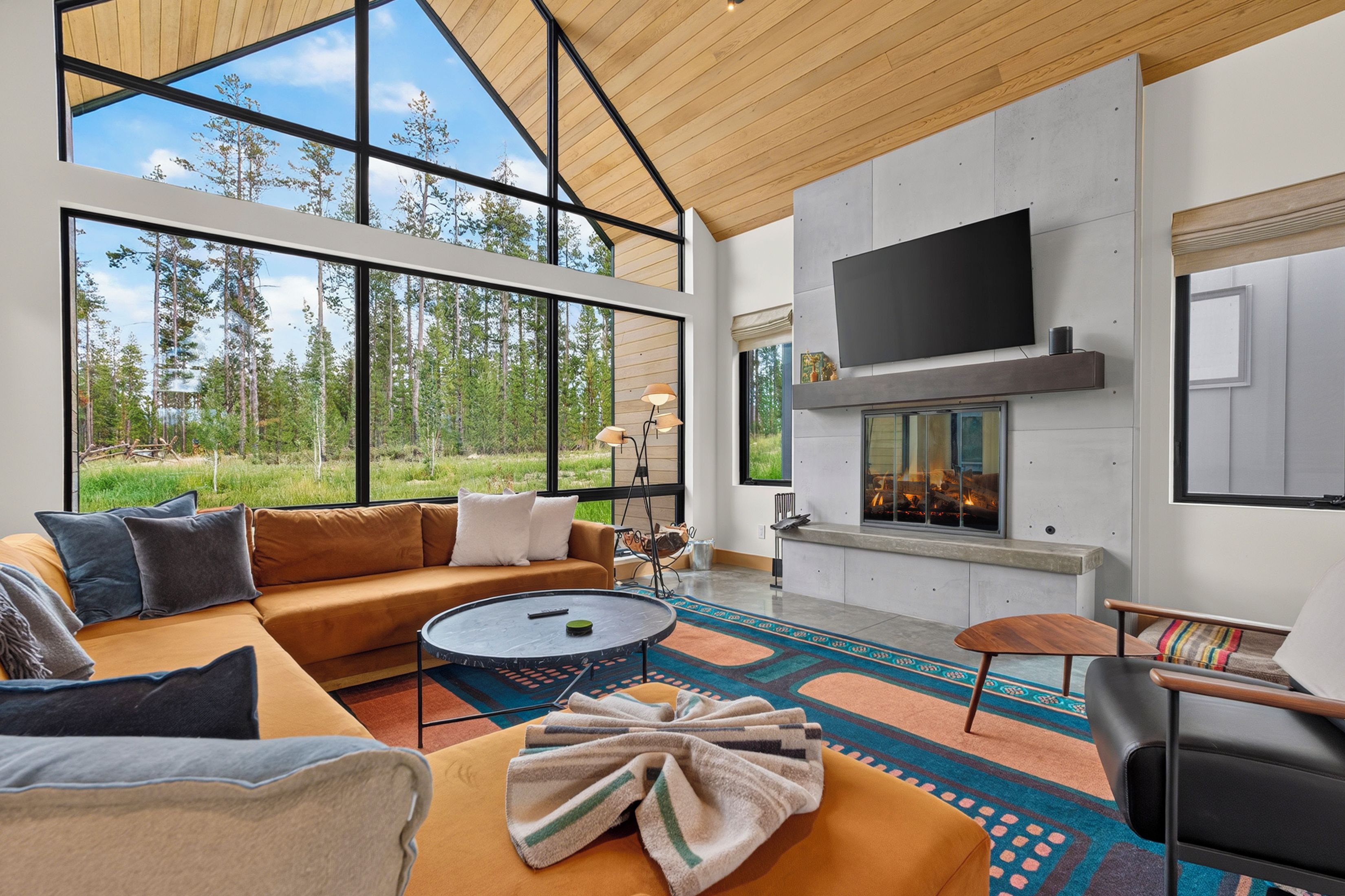 Una sala de estar moderna con un ventanal grande, chimenea y televisor de pantalla plana.