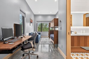 A modern office space with a desk, computer, chair, and a view of the outdoors.