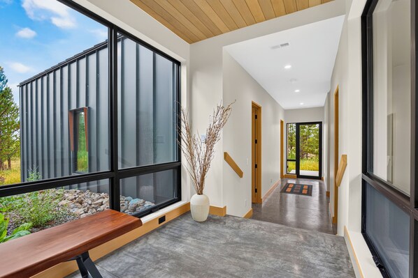 A modern interior with a long hallway, large windows, and a bench.