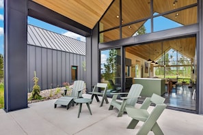 A modern building with a patio area featuring outdoor seating and a view of the interior. - Two Sisters Secludes private home mt views in-floor heating family rental (Tabernash)