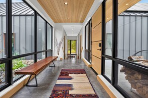 A modern interior with a long corridor, wooden benches, and large windows.
