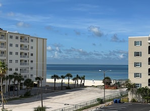 A beachfront property with a clear view of the ocean, a parking area, and a building with multiple floors and balconies. - Mojito Haze- XL Townhome with Rooftop Sunsets, and Redington Beach Views! (Redington Shores)