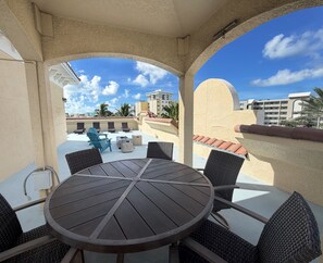A round table with chairs, a view of a building, and a clear sky. - Mojito Haze- XL Townhome with Rooftop Sunsets, and Redington Beach Views! (Redington Shores)