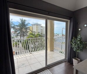 Varanda com vista para palmeiras e edifícios, um vaso de planta e um corrimão.