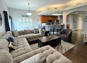 A modern living room with a sectional sofa, a coffee table, and a dining area with bar stools. - Mojito Haze- XL Townhome with Rooftop Sunsets, and Redington Beach Views! (Redington Shores)