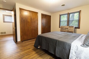 Ein Schlafzimmer mit einem Bett, einem Holzschrank und einem Fenster mit Jalousien.