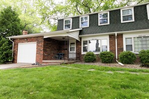 Ein zweistöckiges Haus mit Garage, überdachter Veranda und gepflegtem Rasen.