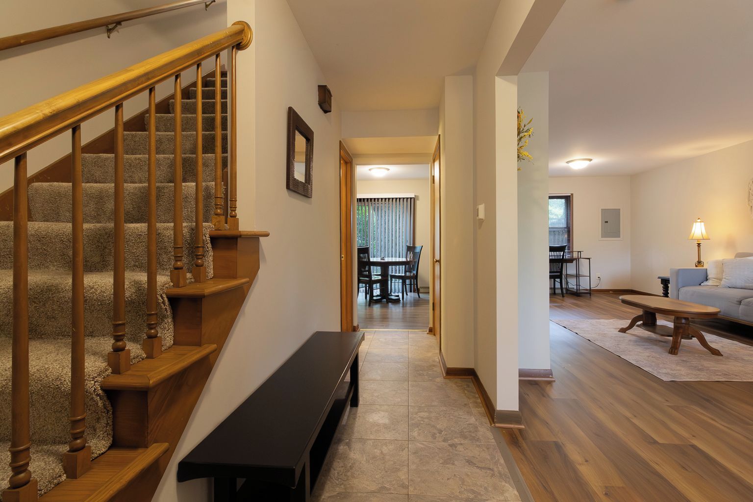 Una escalera con barandillas de madera que lleva a un comedor con una mesa y sillas.