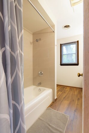 Ein Badezimmer mit einer Badewanne, einer Dusche und einem Fenster.
