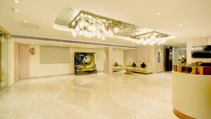 A spacious lobby with a marble floor, a reception desk, a sofa, and a decorative ceiling light fixture. - Palette Naveena Grand Hyderabad (Hyderabad)