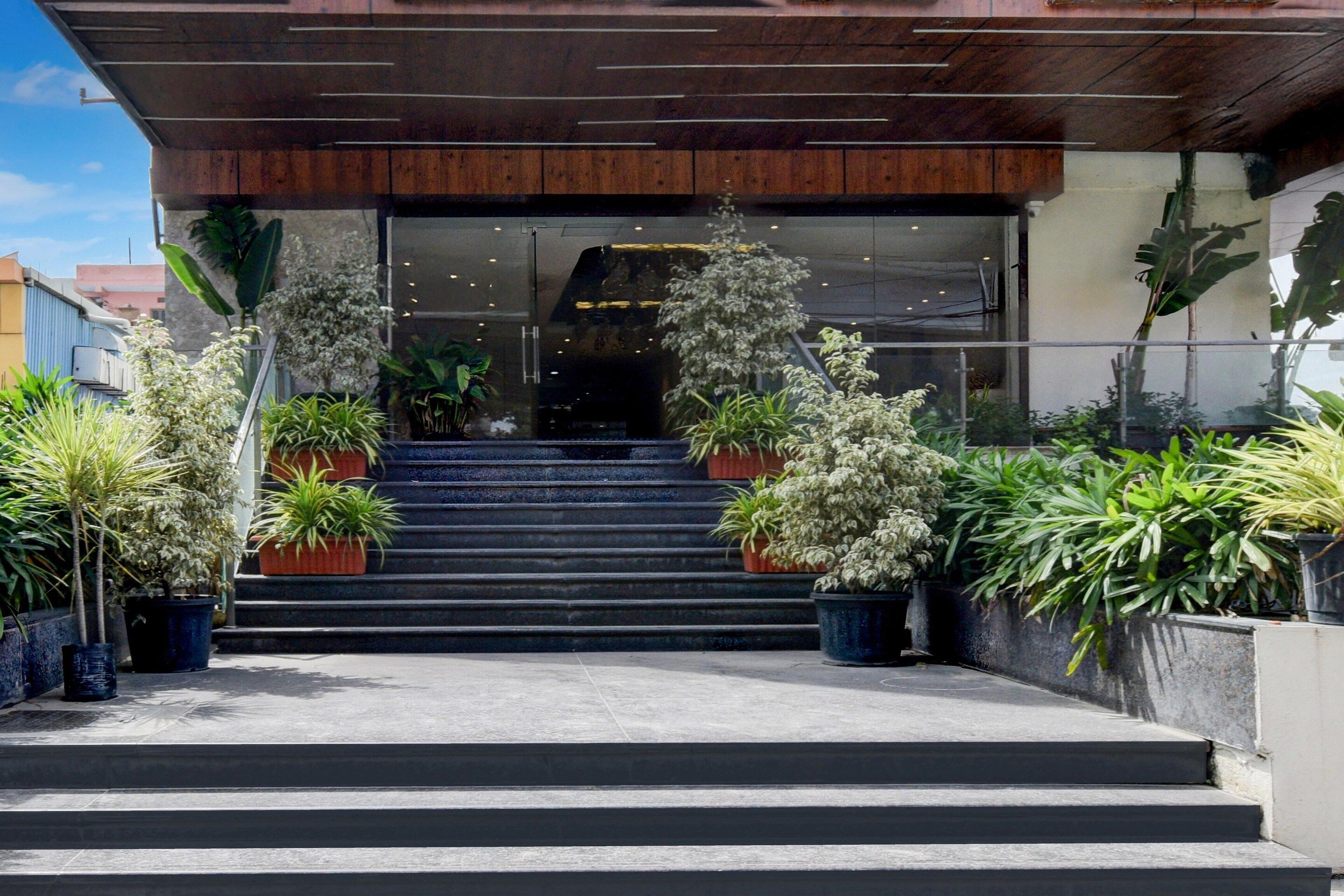 A building entrance with a set of stairs leading up to a glass door, surrounded by potted plants.