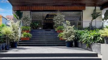 A building entrance with a set of stairs leading up to a glass door, surrounded by potted plants.