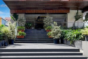 A building entrance with a set of stairs leading up to a glass door, surrounded by potted plants. - Palette Naveena Grand Hyderabad (Hyderabad)