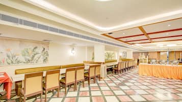 A dining area with high tables and chairs, a patterned floor, and a wall with a tropical plant mural.