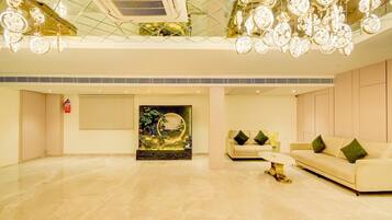 A spacious lobby with a modern chandelier, a sofa, and a decorative wall piece.