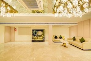 A spacious lobby with a modern chandelier, a sofa, and a decorative wall piece.