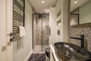 A modern bathroom with a glass-enclosed shower, a freestanding bathtub, and a large mirror. - Renovated, Stylish, 3BR Kadıköy (Istanbul)