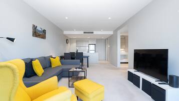 Ein modernes Wohnzimmer mit einer Couch, Hocker und einem Flachbildfernseher.