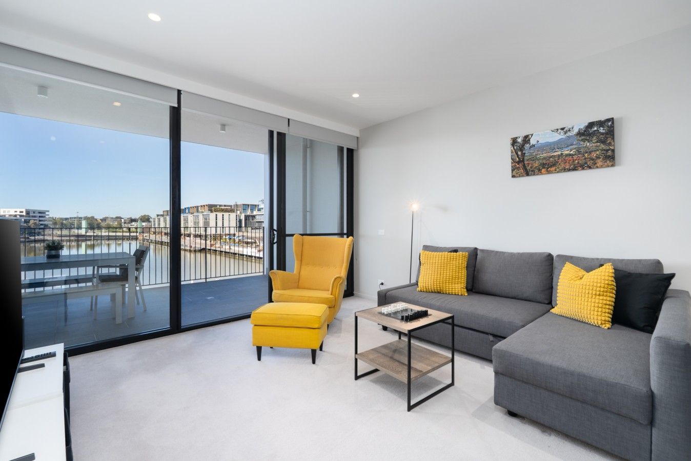 Un salon moderne avec un balcon, un canapé, un fauteuil et une table basse.